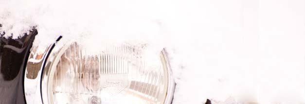 A close up of a motorcycle headlight covered in snow.